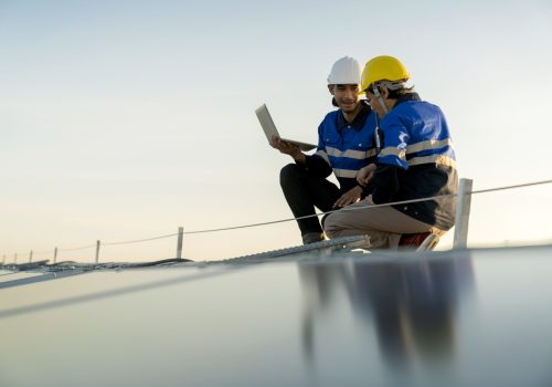 specialist-technician-professional-engineer-with-laptop-tablet-maintenance-checking-installing-solar-roof-panel-factory-rooftop-sunlight-engineers-team-survey-check-solar-panel-roof-min